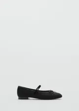Zapato tipo ballerina color negro con puntera redondeada, tira sobre el empeine con hebilla y moño decorativo.