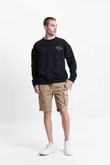 Buzo de felpa negro con estampado en la espalda que incluye la palabra 'Premium' en blanco y naranja, la frase 'Creative Studio' en naranja, y otros textos y gráficos en blanco y naranja. Tiene cuello redondo y puños.