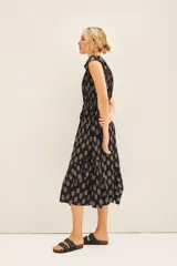 Vestido corto negro con estampado floral blanco, escote en V, volados en mangas y falda, cintura elastizada, frunces en hombros, tajo central y cierre lateral invisible.