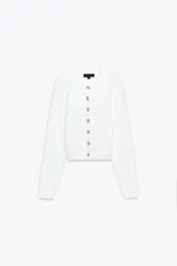 Chaqueta blanca de punto con cuello redondo y manga larga. Cierre frontal con botones con aplicación de joya.