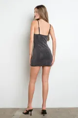 Vestido corto negro ajustado al cuerpo, con escote corazón y tirantes finos. Está completamente cubierto de strass plateados.