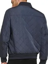 Campera bomber azul marino con diseño acolchado en forma de rombos, cierre frontal con cremallera, cuello, puños y dobladillo acanalados, bolsillos laterales y bolsillo en la manga con cremallera. Logotipo de Calvin Klein en la manga.