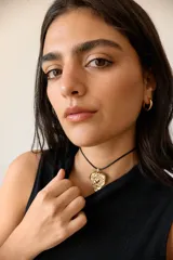 Collar con tiento encerado negro y dije dorado con forma de corazón texturizado.