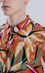 Camisa de manga larga con estampado de flores y hojas en tonos naranja, blanco, rojo, verde y negro.