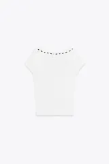 Camiseta blanca de canalé con escote redondo, manga corta y detalle de volantes con cordón negro a contraste.