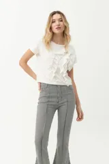 Remera blanca de algodón con cuello redondo y mangas cortas. Presenta volados verticales en el frente.