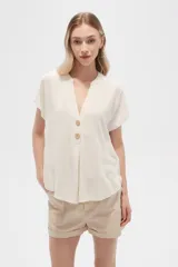 Blusa color crudo de viscosa, corte holgado, con cuello en v y cierre frontal con dos botones de madera.
