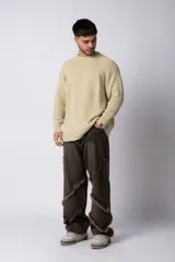 Sweater marrón de punto con cuello redondo y mangas largas raglán. Tejido grueso con textura acanalada. Corte holgado.