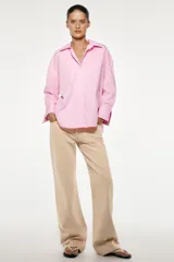 Camisa amarilla de popelina de algodón, con cuello solapa, escote en pico, manga larga con puños y cierre frontal con botones.