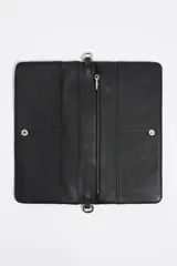 Minibolso negro de estructura blanda con asa de mano de cordón rojo y asa larga extraíble. Presenta logo metálico, acabados metálicos y cierre con botón de presión. Incluye tarjetero interior e interior con logo estampado.