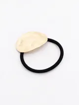 Colero de pelo con elástico negro y aplique metálico dorado con textura irregular.