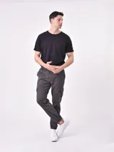 Pantalón jogger gris oscuro con cintura elástica ajustable con cordón, bolsillos laterales y bolsillo cargo con solapa en la pierna. Puños elásticos en los tobillos.
