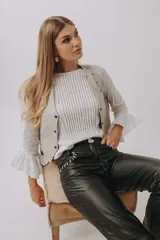 Camisa blanca de mangas largas con volados en los puños, con pechera plisada y chaleco color crema con botones.