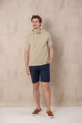 Remera tipo polo color beige, de manga corta y corte clásico. Tiene cuello con botones y está confeccionada en algodón.