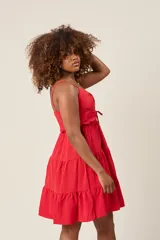 Vestido corto color verde claro, con tirantes finos, detalle de lazo en el escote y falda con volantes escalonados.