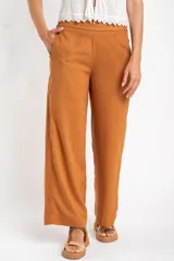 Pantalón de lino color ocre, de corte recto y tiro medio, con lazo de ajuste en la cintura.