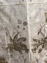 Mantel rectangular de lino y algodón en dos tonos, con estampado artesanal de hojas y flores.