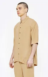 Camisa beige de lino con mangas 3/4, corte oversize y cuello clásico.