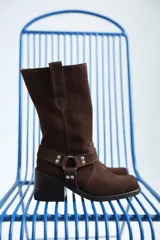 Bota de caña media color marrón chocolate, de gamuza, con taco cuadrado y correa con hebilla metálica alrededor del tobillo.