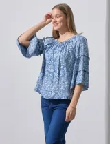 Blusa celeste con estampado floral blanco, escote con frunces y mangas 3/4 con volados.