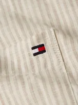 Blusa de lino a rayas verticales color beige y blanco, de corte amplio, manga corta tipo kimono, cuello mao y cierre frontal con botones. Tiene dos bolsillos de parche en el pecho y logo de Tommy Hilfiger bordado.