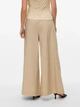 Pantalón oversize de pierna ancha color beige, con pliegues y bolsillos laterales.