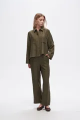 Camisa color natural de poliéster con cuello camisero, cierre con botones, dos bolsillos frontales y corte ancho.