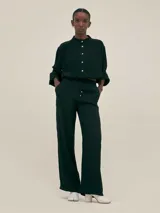 Pantalón palazzo negro de crepe con cintura elastizada, bolsillos laterales y terminaciones con logo en cobre.