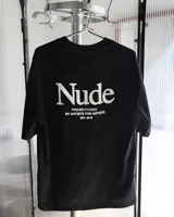 Remera negra de corte recto con estampado en la espalda con la palabra "Nude" en blanco, seguido de "PROJECT®CULT. BY ARTISTS FOR ARTISTS. EST. 2019".