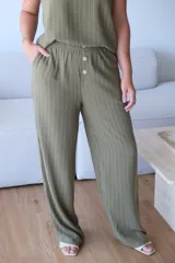 Pantalón ancho de tiro alto, color verde seco con finas rayas verticales blancas. Presenta cintura elastizada y dos botones decorativos frontales.