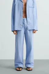 Pantalón de pijama celeste de algodón, corte relaxed fit, con cintura elástica ajustable con cordón interior, bolsillos laterales y detalle de vivos combinados a contraste en el bajo.