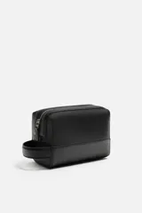 Neceser negro rectangular con cierre de cremallera y asa lateral. El interior tiene un bolsillo con cierre mediante cremallera.