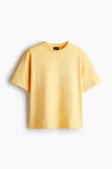 Remera de algodón color amarillo, de corte holgado, con cuello redondo ribeteado, hombros caídos y bajo recto.