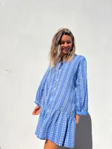 Vestido camisero corto celeste con bordado de flores blancas, corte recto y mangas largas.
