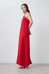 Vestido largo rojo, sin mangas, con escote halter cruzado en el frente y caída recta y holgada.