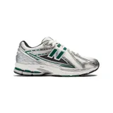 Championes New Balance modelo 1906R, color blanco con detalles en plateado y verde. Presentan el logo "N" en los laterales y tecnología de amortiguación N-ergy en la entresuela.