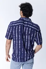 Camisa de manga corta para hombre confeccionada en viscosa, con estampa de arabescos en color azul y blanco. Presenta cuello con solapa y cierre frontal mediante botones.