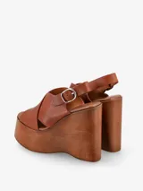 Sandalia negra con plataforma de madera y tira trasera ajustable con hebilla.