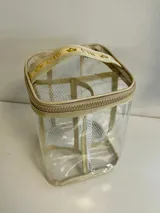 Neceser transparente con cierre superior y manija de tela con logo. Ideal para organizar maquillaje y productos de cuidado personal.