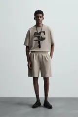 Bermuda color arena de tejido interlock de algodón con elasticidad, corte relaxed fit, cintura elástica ajustable con cordón interior, bolsillos laterales y bolsillo trasero de plastrón.