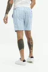 Short de baño largo azul con estampado abstracto de hojas en tonos azules más claros. Posee cintura elástica con cordón de ajuste gris, bolsillos laterales y un bolsillo trasero.