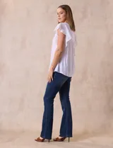 Blusa blanca de gasa con broderie, cuello a la base, escote en V y lazo de ajuste. Delantera broderie con corte y frunces. Manga corta volado de broderie. Espalda con corte y frunces.