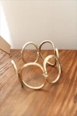 Pulsera de bronce con diseño minimalista y formas ovaladas entrelazadas.