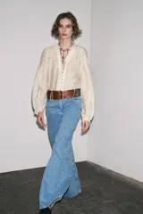 Camisa color crema de algodón con cuello redondo, escote pico con lazadas, manga larga con puños y cierre frontal con botones.
