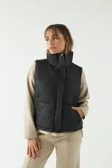 Chaleco puffer color verde oliva con cuello alto y cierre frontal con cremallera.