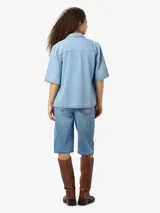 Camisa de denim celeste con cuello clásico, mangas cortas y cierre con botones. Ajuste regular.