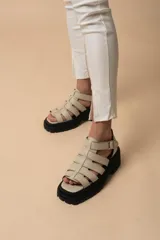 Sandalias de tiras anchas color blanco, con plataforma track negra y hebilla lateral ajustable.