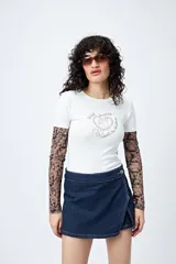 Remera color beige con cuello redondo y mangas cortas. Presenta un estampado con relieve de un corazón con un caballo en su interior y la frase "wild hearts can't be broken".