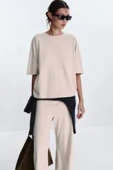 Camiseta color beige de corte amplio, cuello redondo y mangas cortas.
