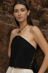 Top negro con espalda descubierta, cuello halter con argolla dorada y tiras de cuero marrón.